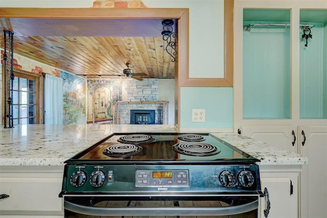 6205 S Choctaw Rd, Choctaw, OK 73020 - kitchen featuring white cabinetry, ceiling fan, wood ceiling, range with electric stovetop, and a stone fireplace