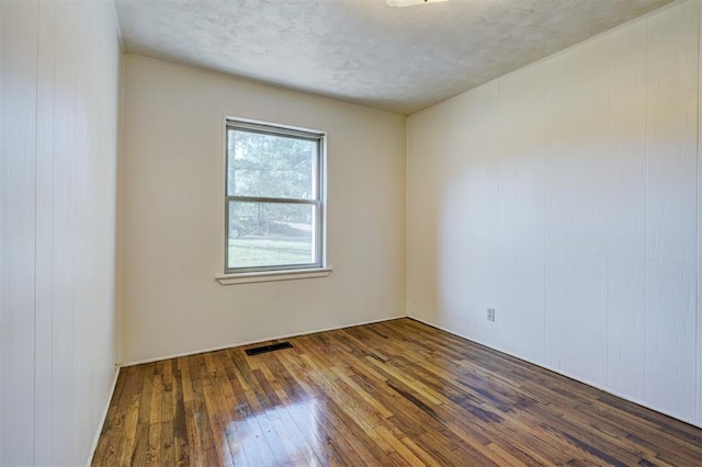 6205 S Choctaw Rd, Choctaw, OK 73020 - spare room with wood-type flooring, a textured ceiling, and visible vents