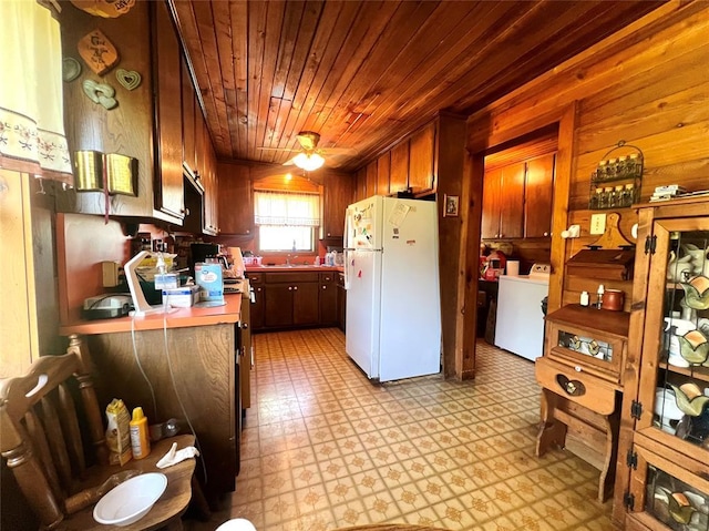 kitchen with washer and clothes dryer, light floors, wooden ceiling, a sink, and freestanding refrigerator
