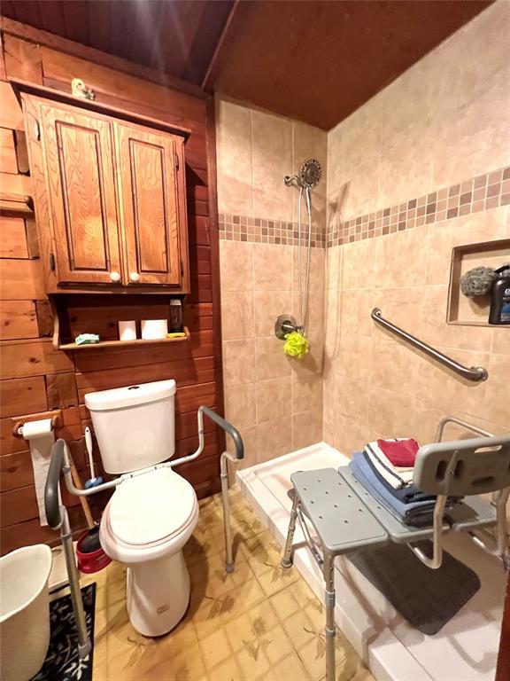full bathroom with tile walls, toilet, and tiled shower
