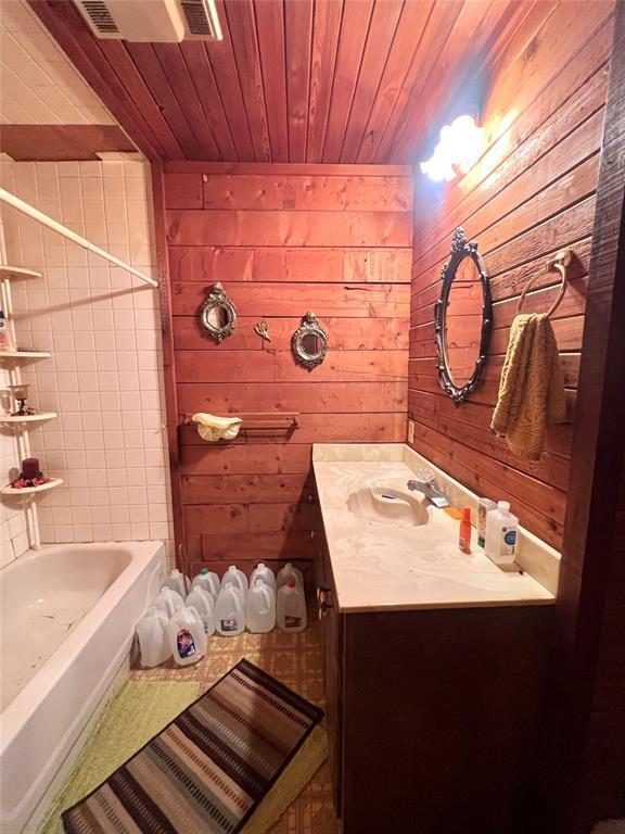 bathroom with visible vents, wooden walls, and vanity