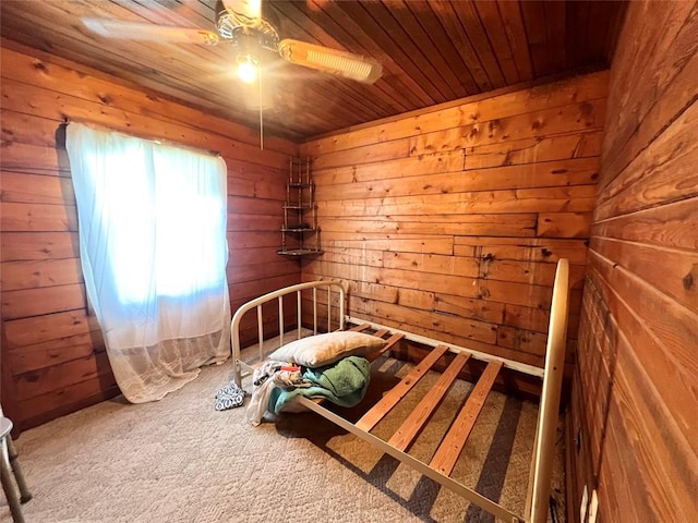 unfurnished bedroom with wooden ceiling, wood walls, carpet flooring, and ceiling fan