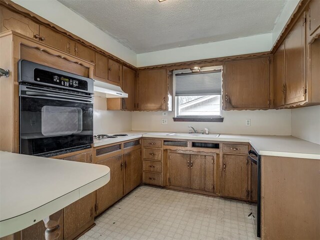 320 Willow Pl, Yukon, OK 73099 - kitchen featuring a sink, brown cabinets, light floors, under cabinet range hood, and black oven
