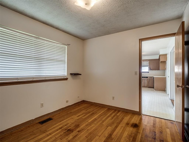 320 Willow Pl, Yukon, OK 73099 - unfurnished room with plenty of natural light, light wood-style floors, visible vents, and a textured ceiling