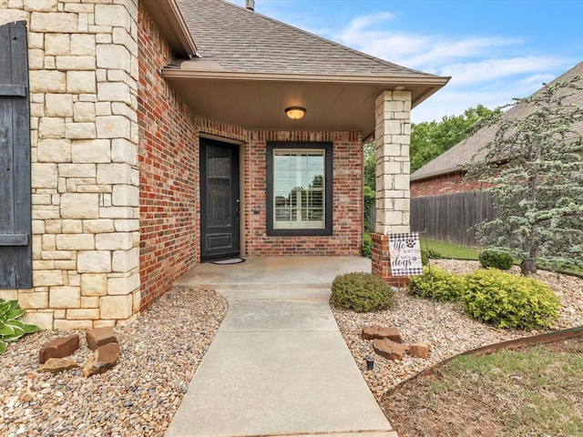 13401 Grapevine Trl, Oklahoma City, OK 73170 - doorway to property featuring brick siding, roof with shingles, and fence