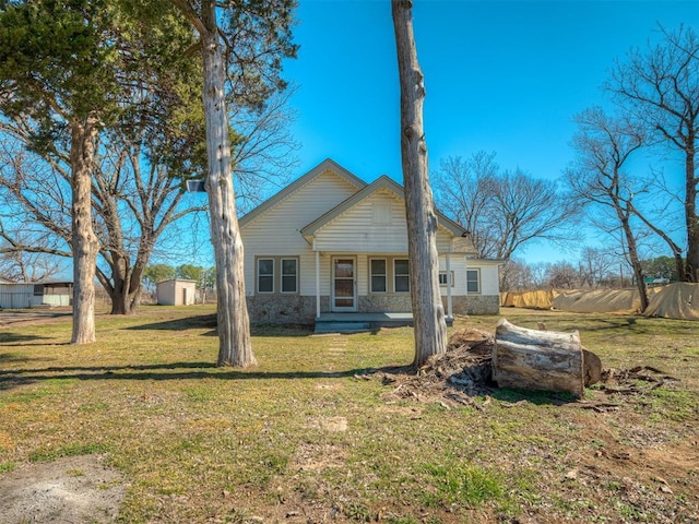 back of house with stone siding, covered porch, and a yard