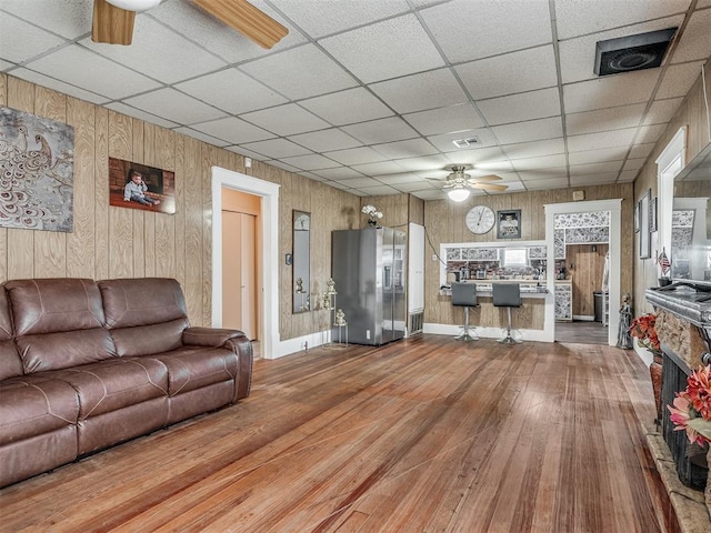 living room with ceiling fan, hardwood / wood-style floors, and a paneled ceiling