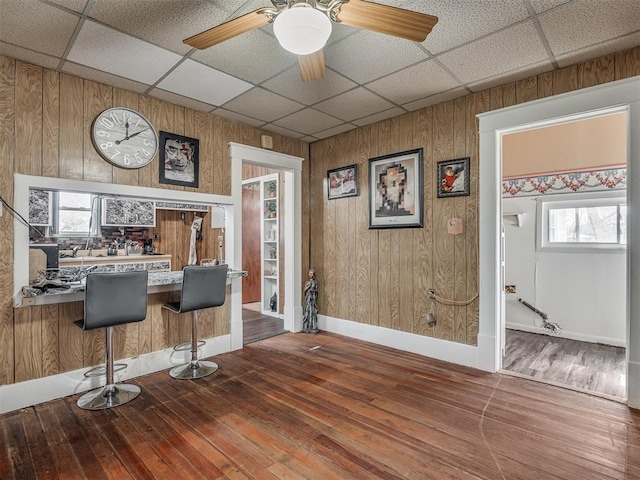bar with hardwood / wood-style floors and a drop ceiling