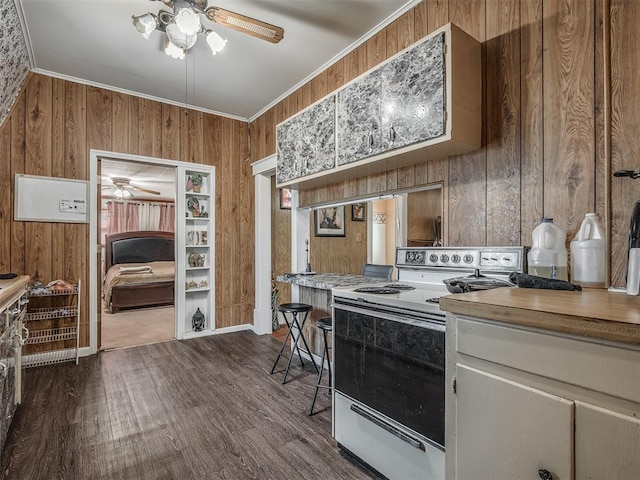 kitchen with ceiling fan, wood walls, white range with electric stovetop, crown molding, and dark wood-style flooring