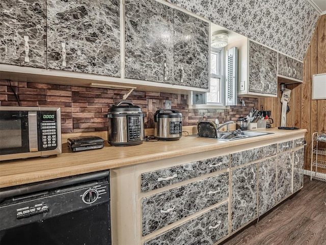 kitchen with a sink, stainless steel microwave, dark wood-style flooring, backsplash, and dishwasher