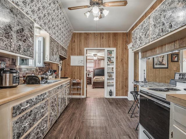 kitchen featuring wood walls, light countertops, ornamental molding, electric range, and ceiling fan