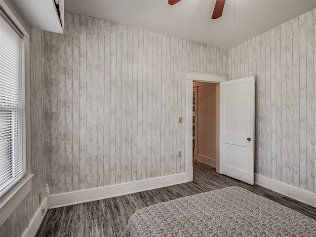bedroom with baseboards, wood walls, and wood finished floors