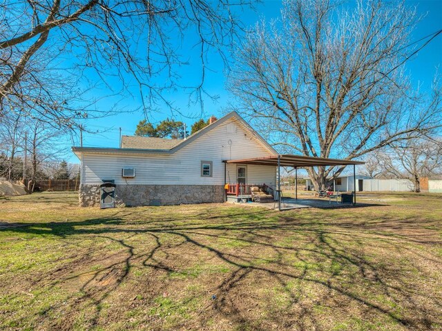 rear view of property featuring a lawn, a carport, and a chimney