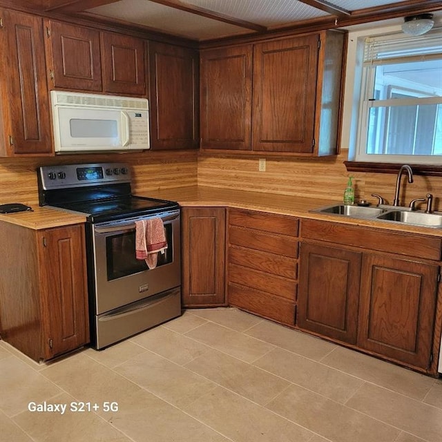kitchen featuring stainless steel electric range oven, light countertops, white microwave, and a sink