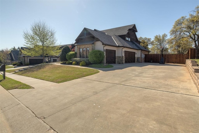 view of home's exterior with a garage, fence, driveway, stone siding, and a yard