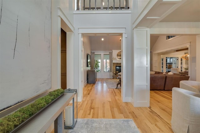 interior space with a fireplace, light wood-style flooring, and a towering ceiling