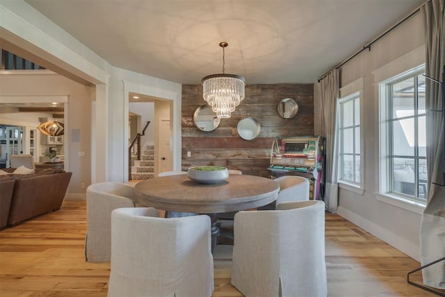 dining area featuring baseboards, light wood-style flooring, stairs, and a chandelier