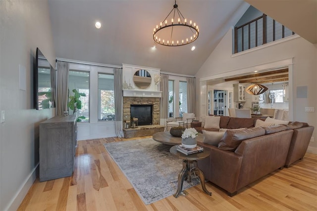 living area with high vaulted ceiling, an inviting chandelier, light wood finished floors, and a fireplace