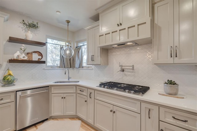 kitchen with a sink, appliances with stainless steel finishes, backsplash, and light countertops