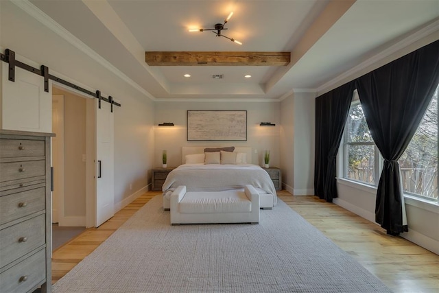 bedroom with baseboards, multiple windows, light wood-type flooring, and a barn door