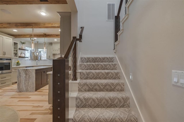 stairway with visible vents, beam ceiling, wood finished floors, baseboards, and recessed lighting