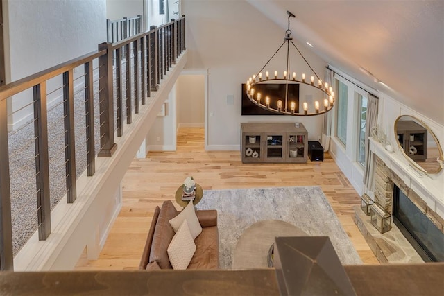 interior space featuring baseboards, wood finished floors, a notable chandelier, and vaulted ceiling