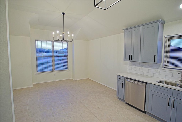 kitchen with a chandelier, stainless steel dishwasher, gray cabinetry, and a sink