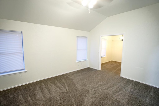 empty room featuring a ceiling fan, baseboards, dark carpet, and vaulted ceiling