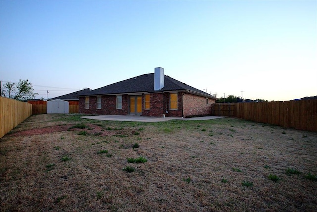 rear view of property featuring a fenced backyard, an outbuilding, a patio area, and a storage unit