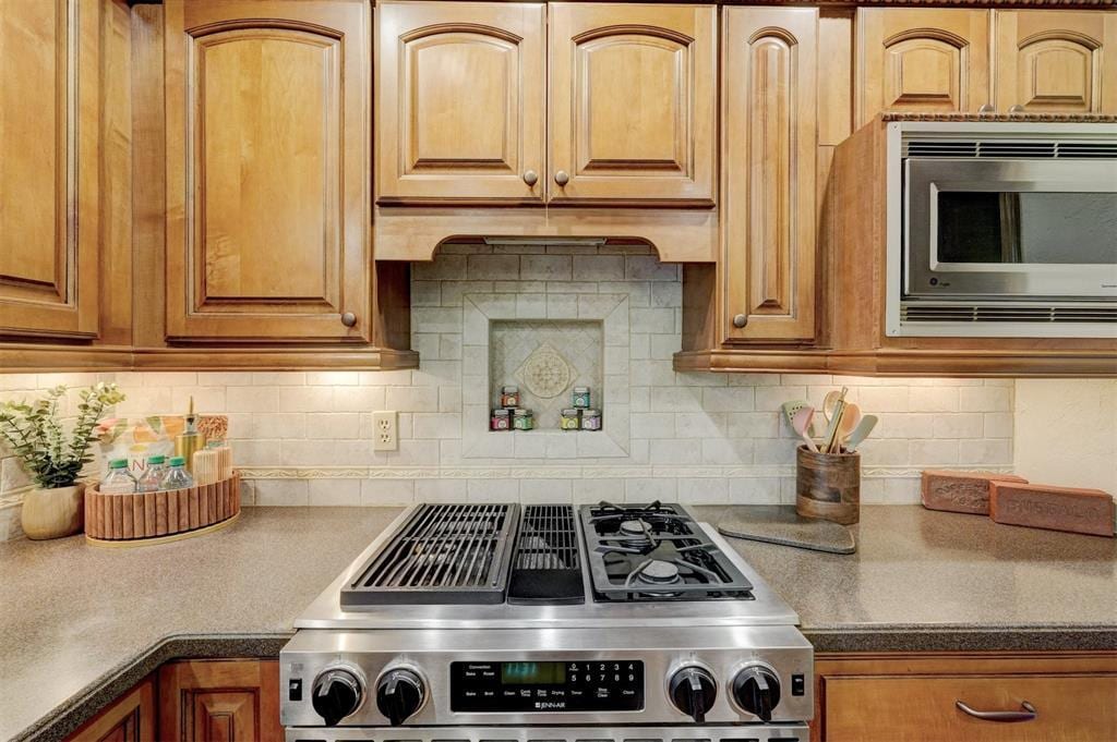 kitchen featuring brown cabinets, appliances with stainless steel finishes, and decorative backsplash