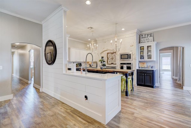 kitchen with light countertops, arched walkways, stainless steel appliances, and baseboards