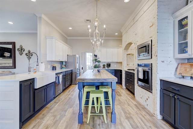 kitchen featuring a breakfast bar area, white cabinetry, a sink, a chandelier, and stainless steel appliances