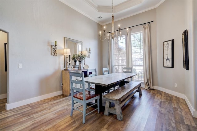 dining space featuring ornamental molding, baseboards, a chandelier, and light wood-style floors