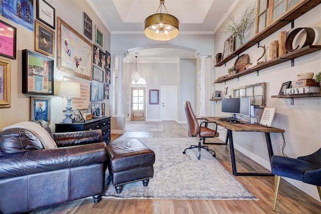 office space featuring arched walkways, wood finished floors, baseboards, ornate columns, and crown molding