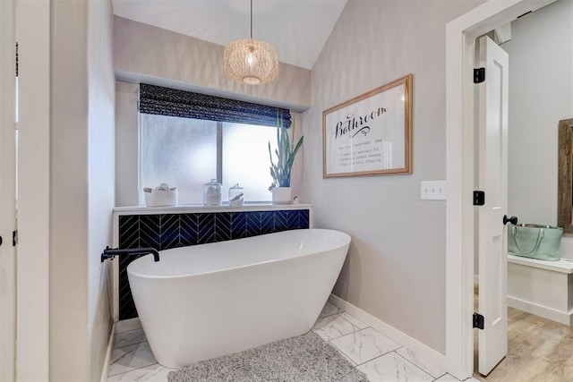 full bath with baseboards, vaulted ceiling, a freestanding bath, and marble finish floor