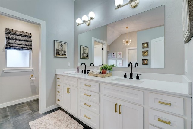 bathroom with double vanity, a sink, lofted ceiling, and baseboards
