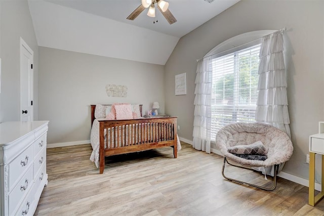 bedroom with light wood-type flooring, a ceiling fan, vaulted ceiling, and baseboards