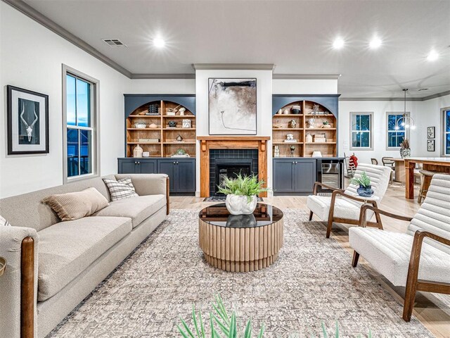 18443 Boardwalk Xing, Norman, OK 73072 - living room featuring crown molding, light wood-style flooring, visible vents, and built in shelves