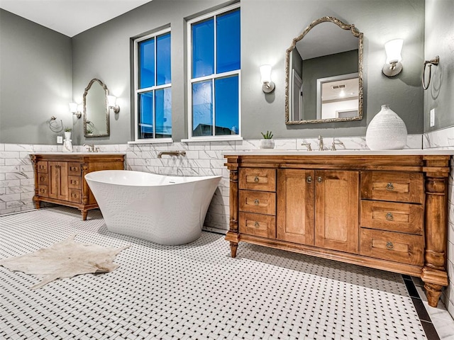 18443 Boardwalk Xing, Norman, OK 73072 - full bathroom with two vanities, tile walls, a freestanding bath, and a wainscoted wall