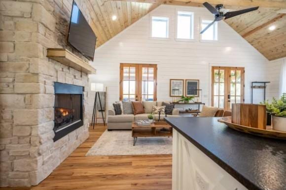 119 Leadwood Trl, Broken Bow, OK 74728 - living room featuring light wood finished floors, french doors, a ceiling fan, a stone fireplace, and high vaulted ceiling