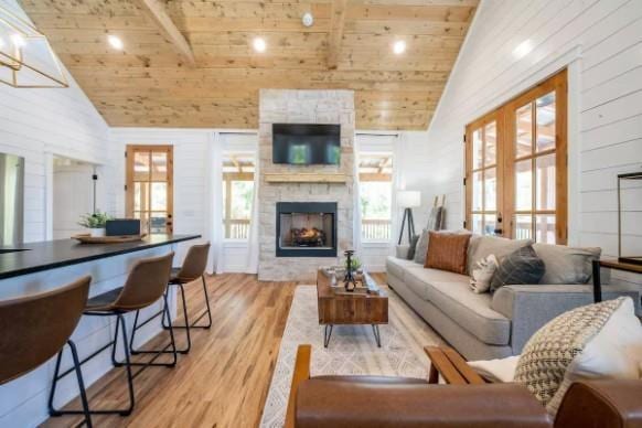 119 Leadwood Trl, Broken Bow, OK 74728 - living room with light wood finished floors, wood walls, wood ceiling, a stone fireplace, and high vaulted ceiling