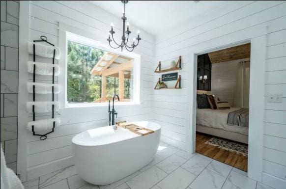 119 Leadwood Trl, Broken Bow, OK 74728 - ensuite bathroom featuring wooden walls, ensuite bath, marble finish floor, and an inviting chandelier