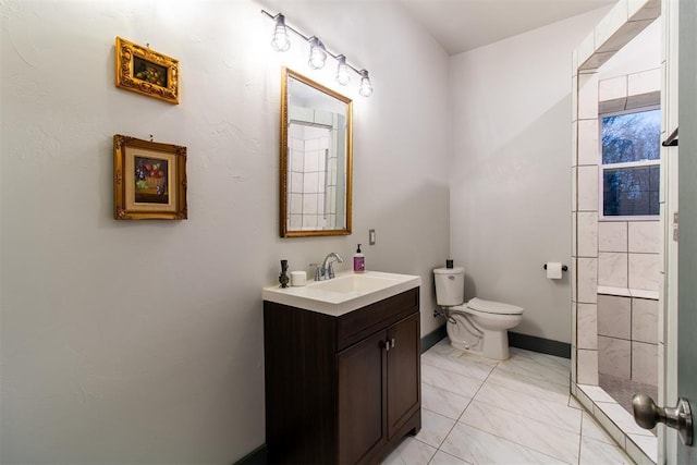 full bathroom with vanity, marble finish floor, toilet, baseboards, and tiled shower