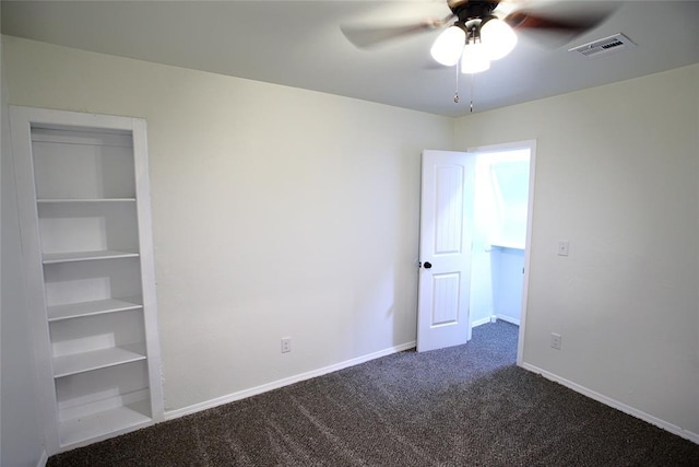 unfurnished bedroom featuring dark colored carpet, visible vents, baseboards, and ceiling fan