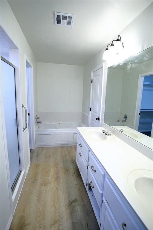 bathroom with a shower stall, wood finished floors, visible vents, and a sink