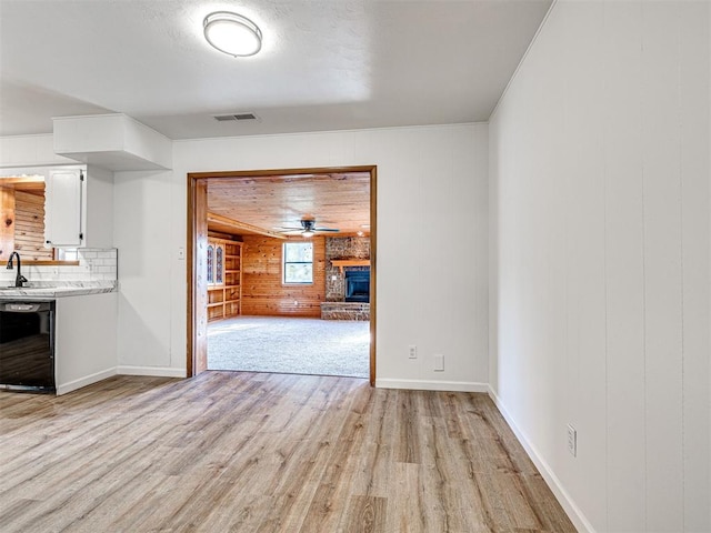3402 Oakhurst Dr, Oklahoma City, OK 73110 - unfurnished living room featuring a sink, baseboards, visible vents, light wood-style floors, and wood walls