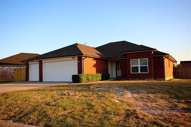 ranch-style house with fence, driveway, brick siding, a front yard, and a garage