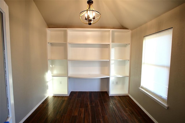 unfurnished dining area with lofted ceiling, baseboards, an inviting chandelier, and dark wood-type flooring