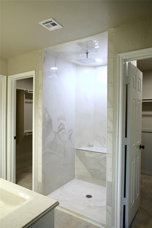 full bath with visible vents, a sink, and a marble finish shower