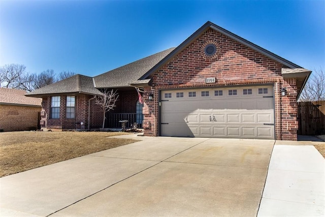 ranch-style house with a shingled roof, concrete driveway, an attached garage, brick siding, and a front yard